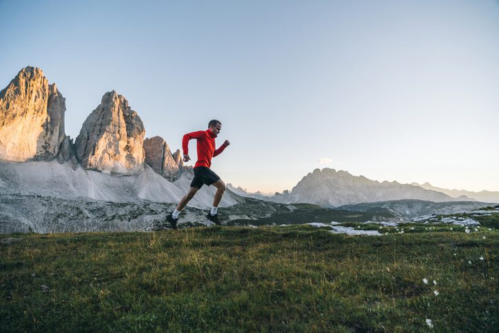 Trail runner in red jacket near mountain peaks